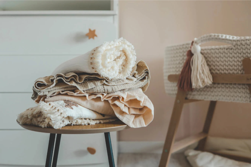 Stack of baby blankets piled on a chair. 