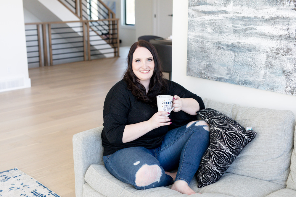 Kara of The Kara Report sits on couch with a cup of coffee as she debunks Pinterest myths.