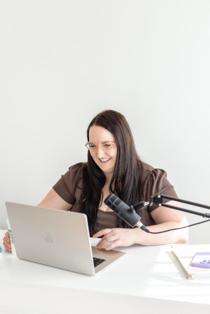 Kara records with microphone as she discusses growing your podcast with Pinterest and blog content.
