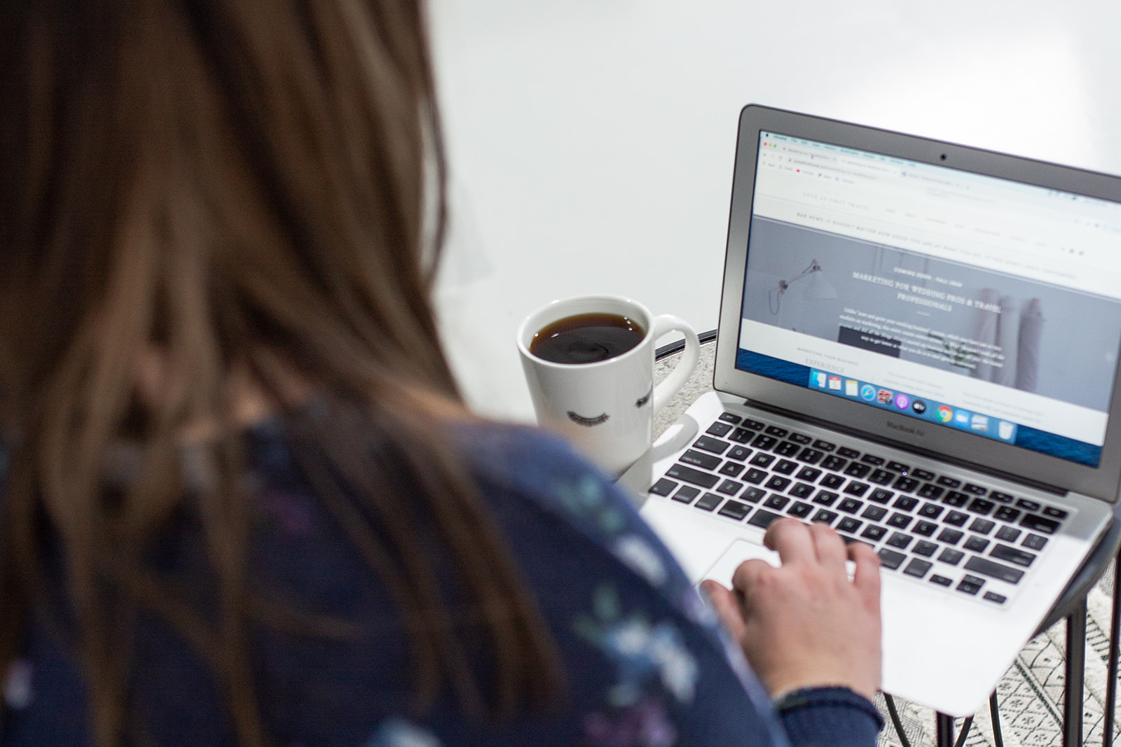 Woman types out blog post on laptop from a podcast episode she recorded.