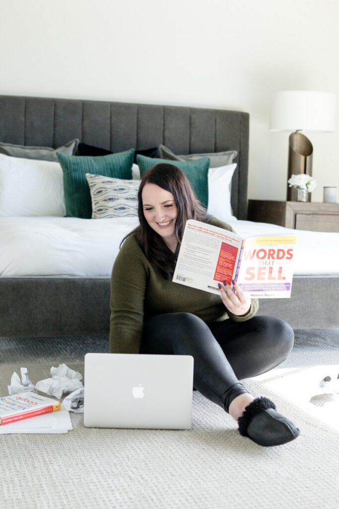 blog writer reading book called words that sell while creating a lead magnet on her laptop
