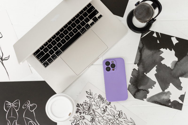 Flat lay of a laptop, headphones, coffee, and phone surrounded by creative sketches and marketing ideas for content planning and small business strategy.